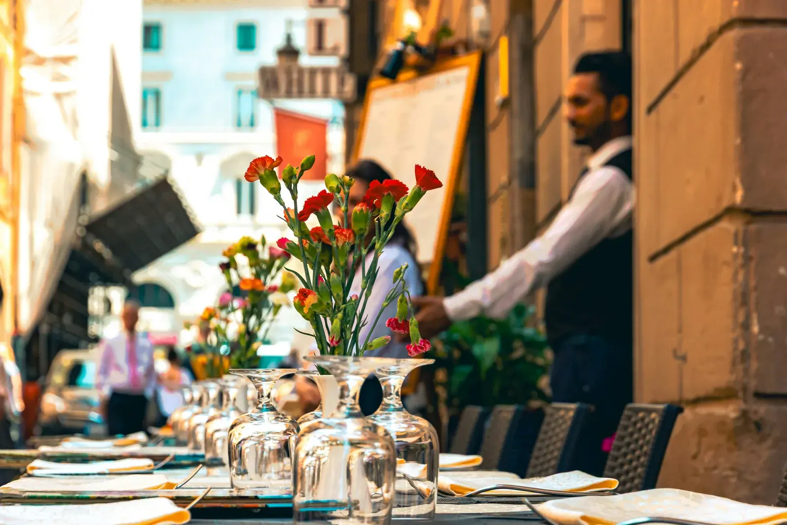 A server laying a table on a sunlit terrace